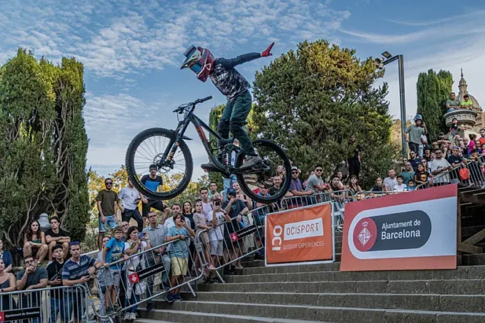 Ciclistas compitiendo en el descenso urbano de Montjuïc, Barcelona, atravesando rampas y escaleras en un emocionante circuito lleno de obstáculos.